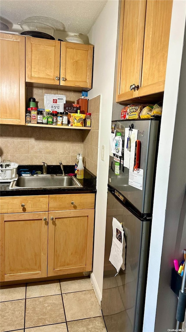 kitchen featuring stainless steel fridge, tasteful backsplash, a textured ceiling, sink, and light tile patterned flooring