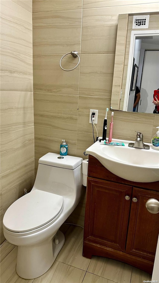 bathroom with vanity, tile walls, and toilet