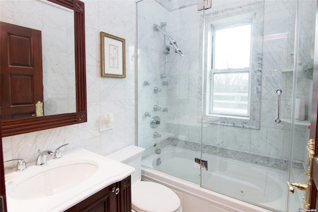 full bathroom with shower / bath combination with glass door, vanity, toilet, and tile walls