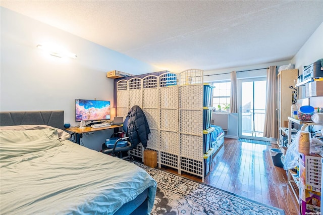 bedroom featuring hardwood / wood-style floors, a textured ceiling, and access to outside