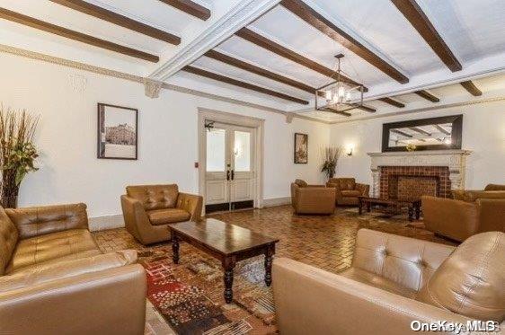 living room featuring a fireplace, beamed ceiling, and french doors