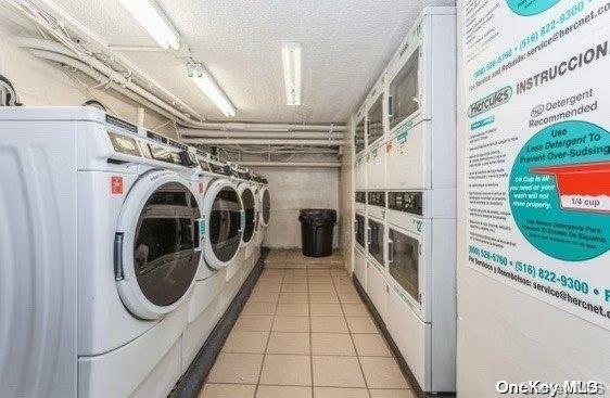 laundry room with washer and clothes dryer, light tile patterned floors, stacked washer / dryer, and a textured ceiling