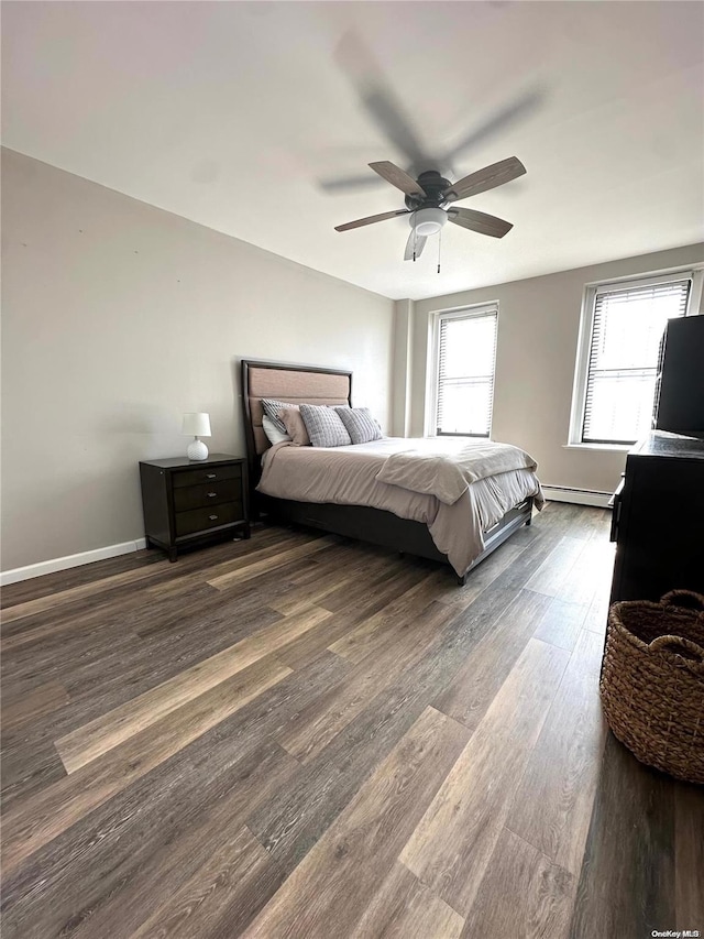 bedroom with baseboard heating, multiple windows, ceiling fan, and dark wood-type flooring