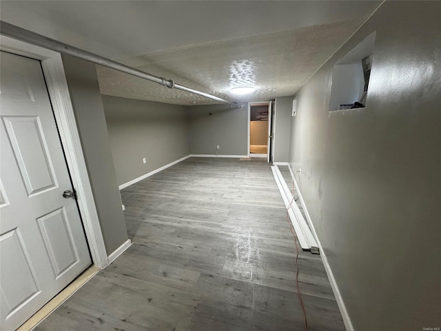 basement featuring wood-type flooring and a textured ceiling