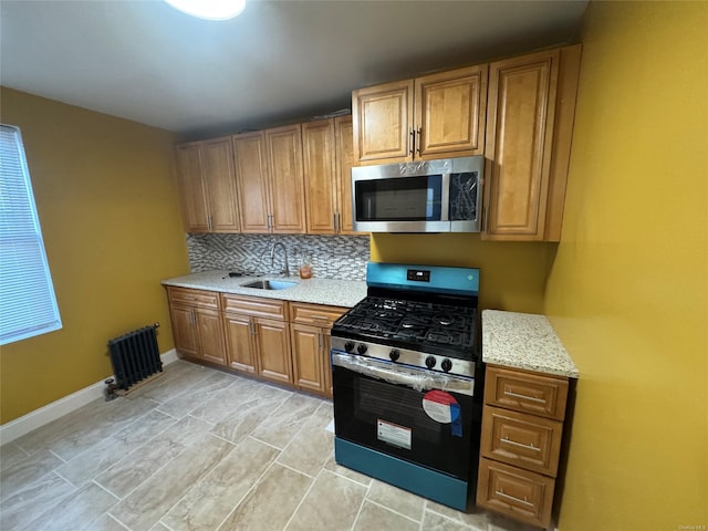 kitchen featuring decorative backsplash, light stone counters, sink, and appliances with stainless steel finishes