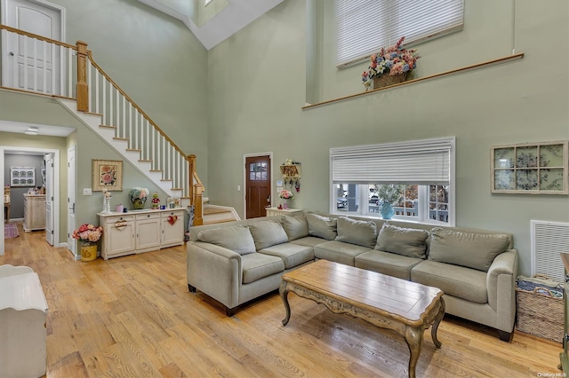 living room with a towering ceiling and light wood-type flooring