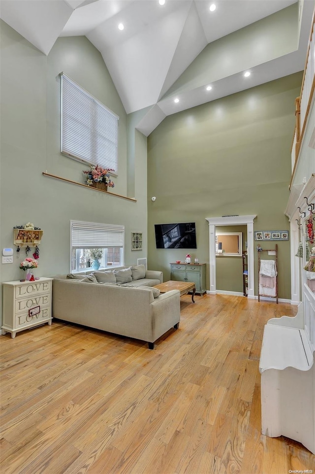 living room with high vaulted ceiling and light wood-type flooring