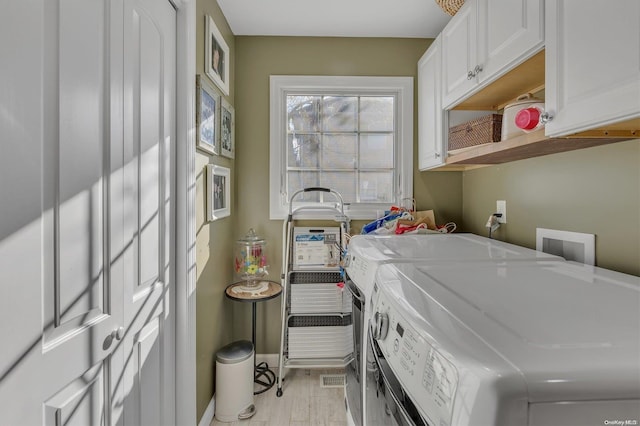 washroom with independent washer and dryer, light hardwood / wood-style flooring, and cabinets