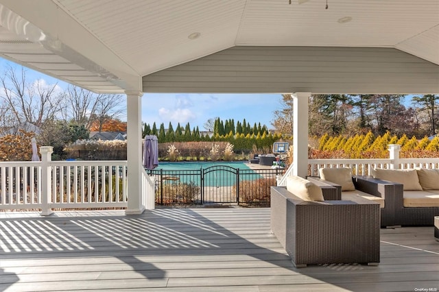 wooden deck with an outdoor hangout area, a fenced in pool, and a patio area