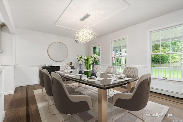 dining area featuring hardwood / wood-style floors, a baseboard radiator, and an inviting chandelier