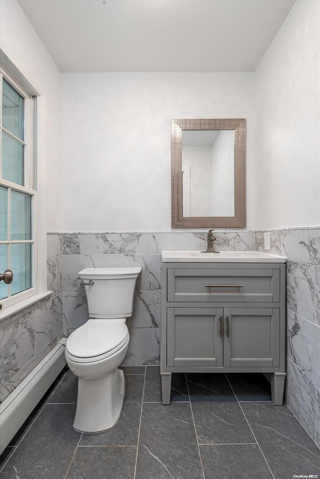 bathroom with a wealth of natural light, tile patterned flooring, tile walls, and toilet