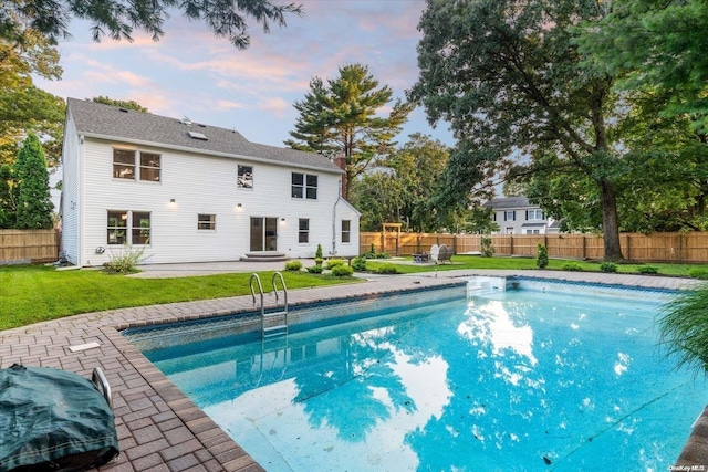 pool at dusk with a yard and a patio