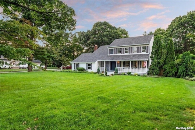 colonial-style house featuring a porch and a yard