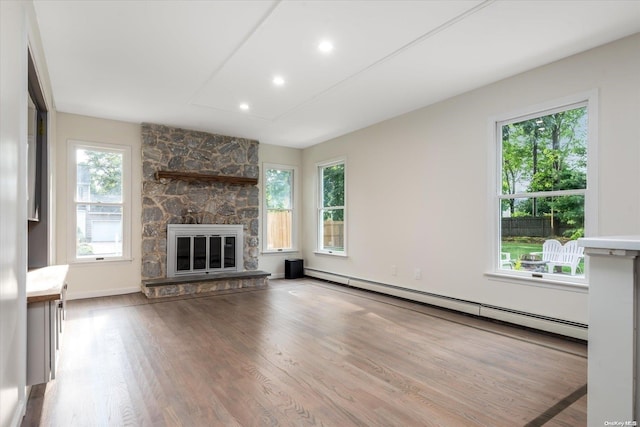 unfurnished living room with a fireplace, hardwood / wood-style floors, and a baseboard heating unit