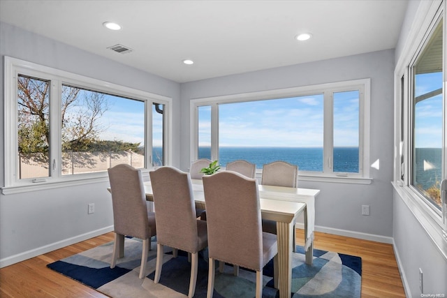 dining space featuring plenty of natural light, a water view, and light hardwood / wood-style flooring