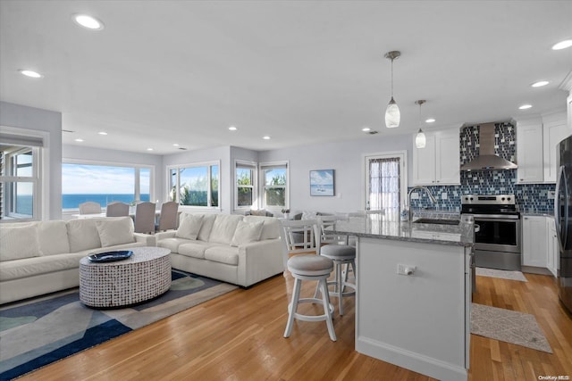 living room with light hardwood / wood-style floors, a water view, and sink