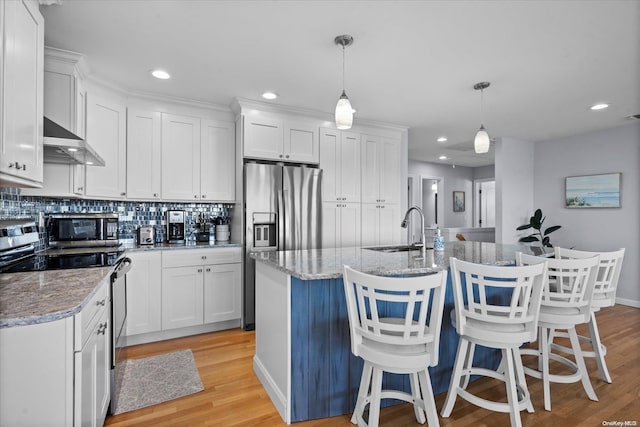 kitchen with white cabinetry, wall chimney range hood, and hanging light fixtures