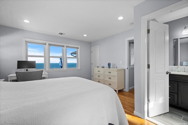 bedroom featuring ensuite bathroom and light hardwood / wood-style floors