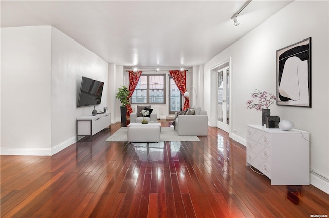 living room with dark hardwood / wood-style flooring and rail lighting