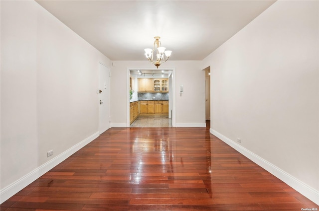 unfurnished dining area with a notable chandelier and dark hardwood / wood-style flooring