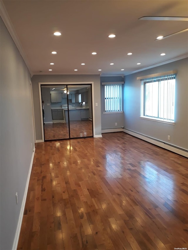 unfurnished room featuring hardwood / wood-style flooring, ornamental molding, and a baseboard radiator