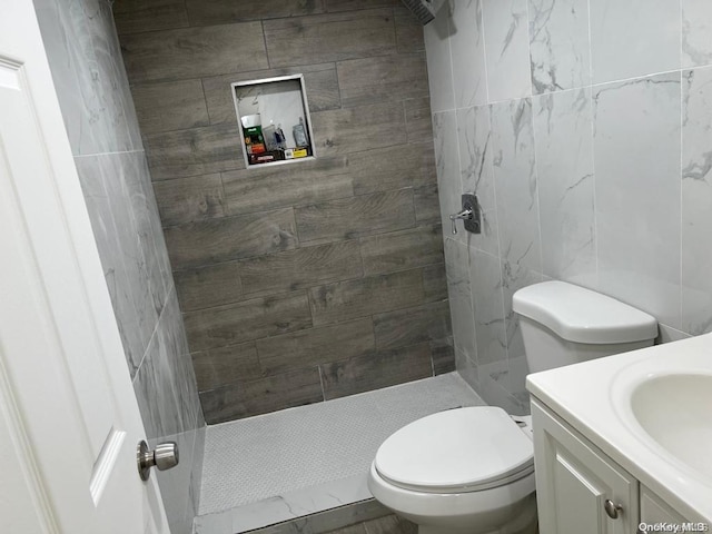 bathroom featuring tiled shower, vanity, and toilet