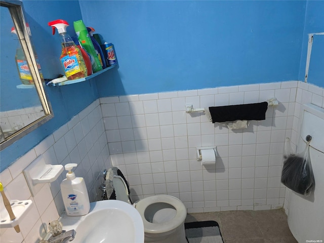 bathroom featuring tile patterned flooring, toilet, sink, and tile walls