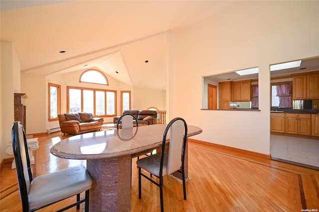 dining area with a baseboard radiator, lofted ceiling, and light wood-type flooring