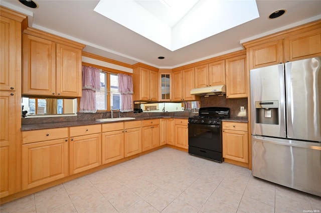 kitchen featuring black gas range oven, sink, a skylight, stainless steel fridge with ice dispenser, and decorative backsplash