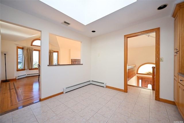 tiled spare room featuring a baseboard heating unit and a skylight