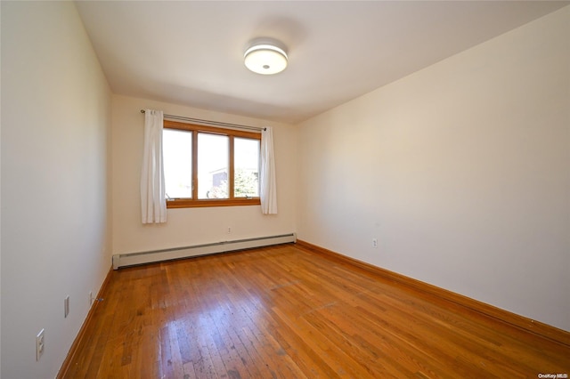 spare room with baseboard heating and light hardwood / wood-style floors