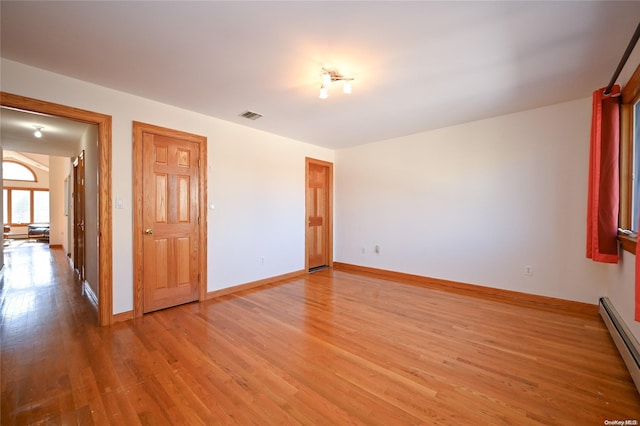 spare room featuring a baseboard radiator and light hardwood / wood-style flooring