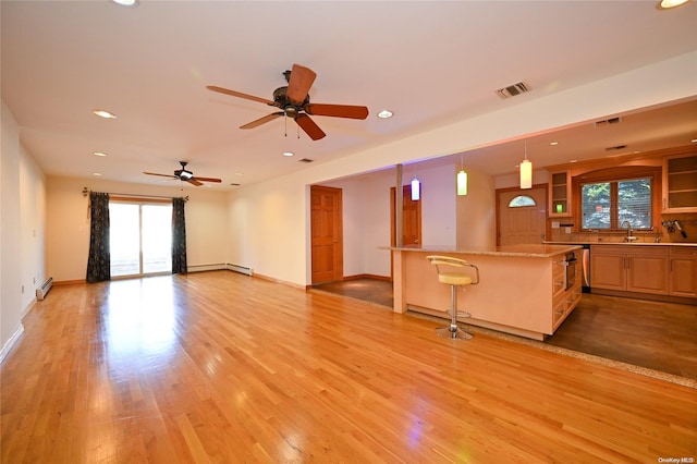 unfurnished living room with ceiling fan, light hardwood / wood-style floors, and a baseboard heating unit