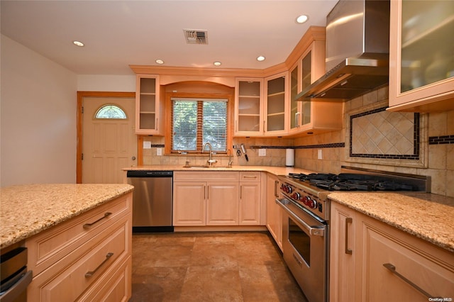 kitchen with stainless steel appliances, light stone countertops, sink, and wall chimney exhaust hood