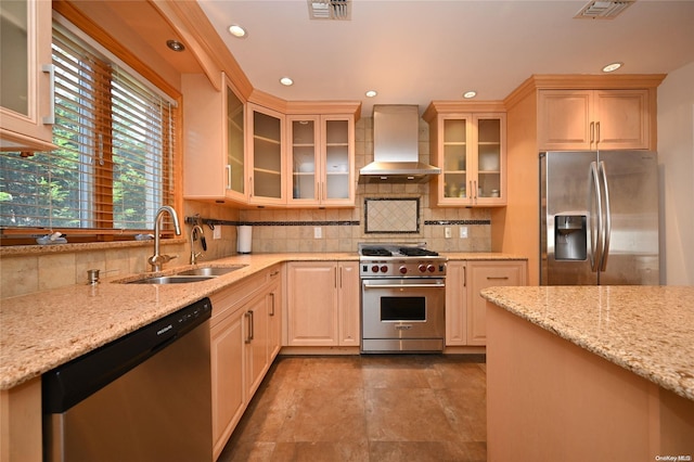 kitchen with sink, light stone counters, wall chimney range hood, stainless steel appliances, and backsplash