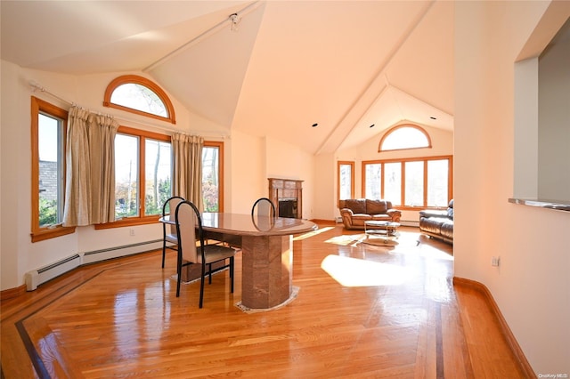 dining room featuring plenty of natural light, high vaulted ceiling, light hardwood / wood-style floors, and baseboard heating