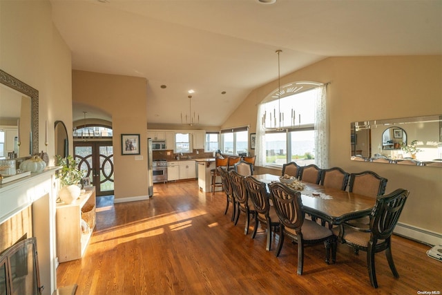 dining area with a tile fireplace, hardwood / wood-style flooring, lofted ceiling, and sink