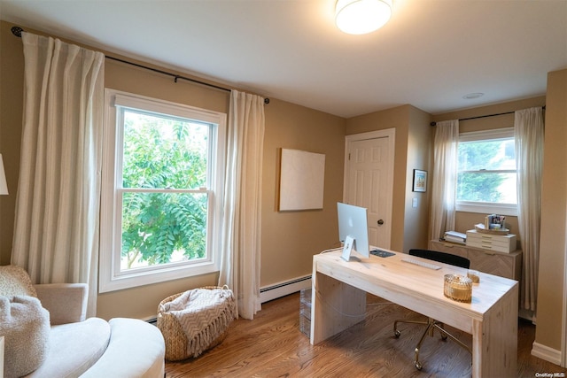 home office featuring a baseboard heating unit, light hardwood / wood-style flooring, and a healthy amount of sunlight