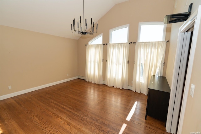 unfurnished dining area with vaulted ceiling, hardwood / wood-style flooring, an inviting chandelier, and baseboard heating