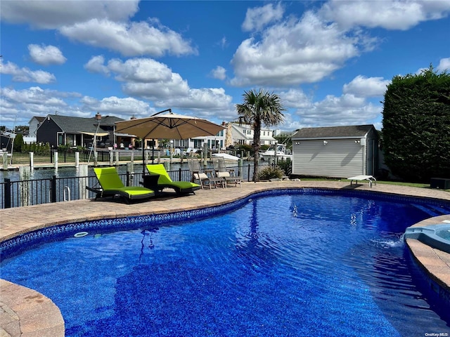 view of swimming pool with a water view and a storage unit