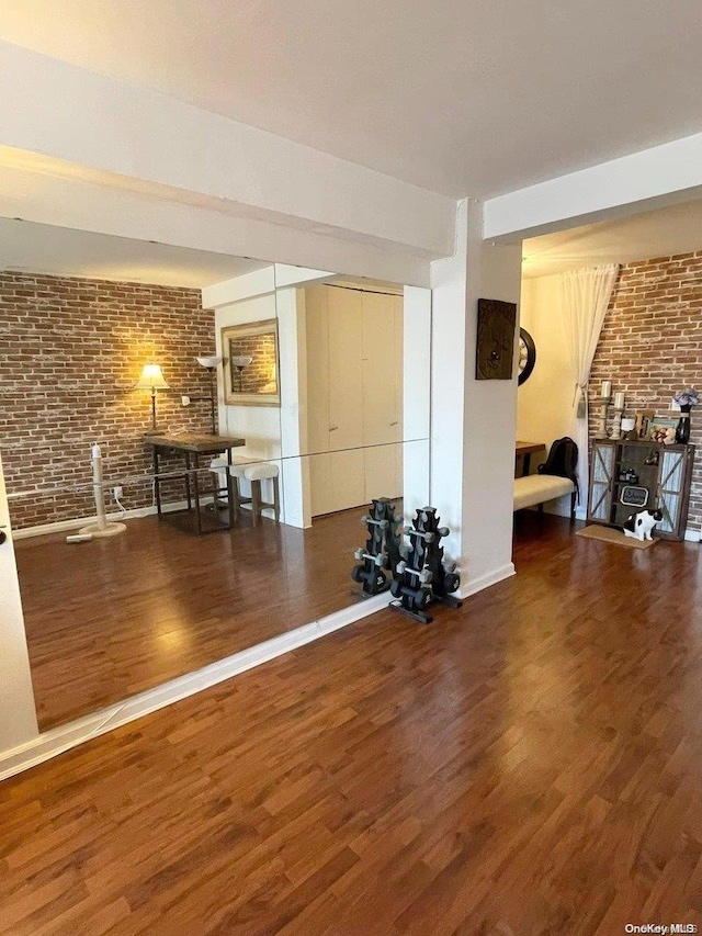 exercise area featuring dark hardwood / wood-style flooring and brick wall