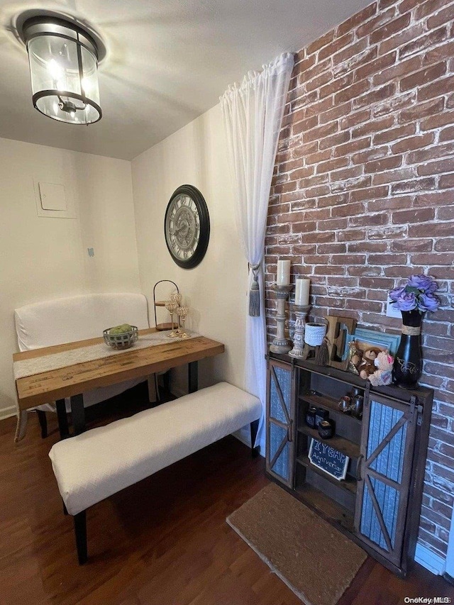 dining room featuring dark wood-type flooring and brick wall