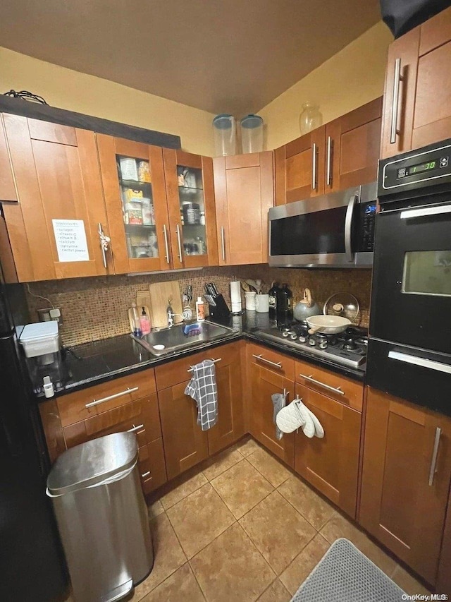 kitchen with black appliances, backsplash, light tile patterned floors, and sink