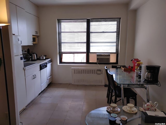 kitchen with radiator heating unit, white appliances, white cabinetry, and cooling unit