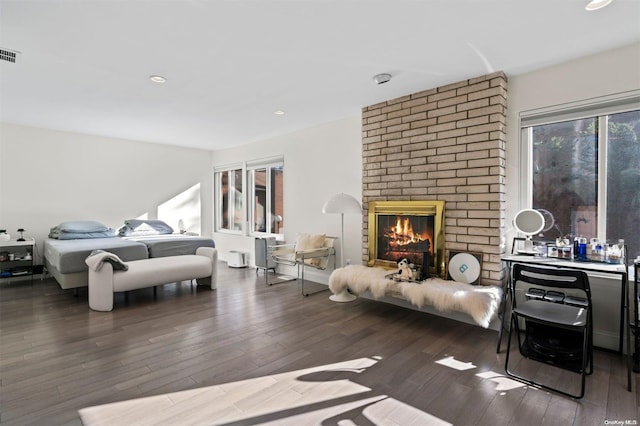 bedroom featuring dark hardwood / wood-style flooring and a brick fireplace