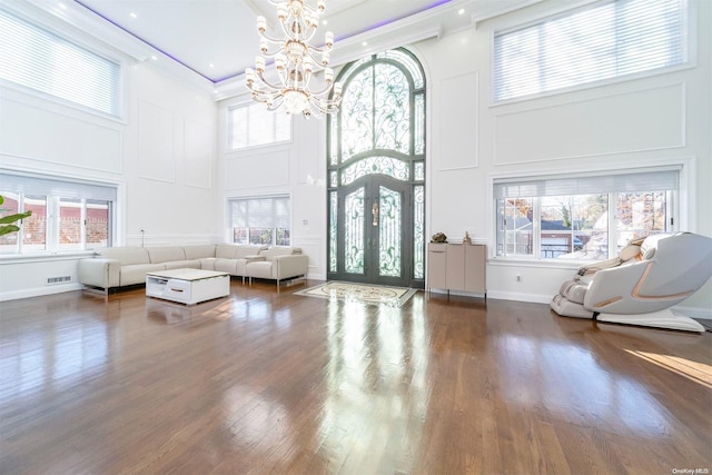 living room featuring a towering ceiling, ornamental molding, dark hardwood / wood-style floors, and a notable chandelier