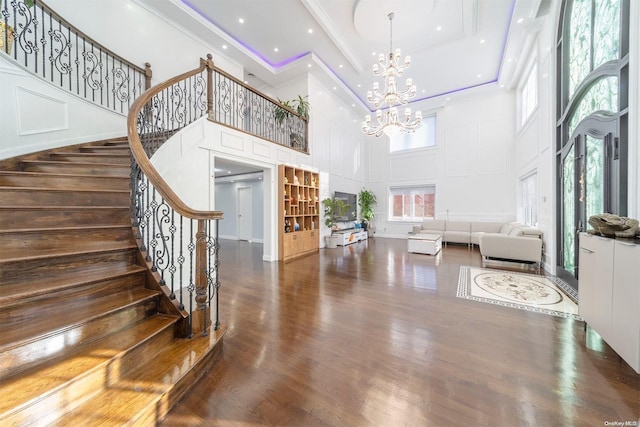 interior space with a chandelier, a towering ceiling, a healthy amount of sunlight, and dark hardwood / wood-style floors