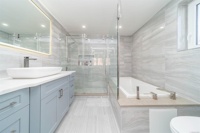 full bathroom with tile patterned floors, vanity, tile walls, shower with separate bathtub, and toilet