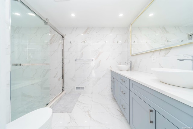 bathroom with vanity, a shower with shower door, tile walls, and toilet