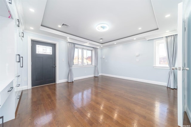 foyer entrance with dark hardwood / wood-style flooring, a raised ceiling, and crown molding